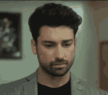 a man with a beard wearing a suit and black shirt