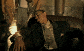 a man in a suit and tie rests his head on a couch