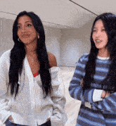 two women are standing next to each other with their arms crossed and one is wearing a striped shirt