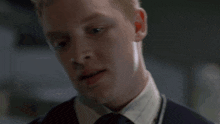 a close up of a man 's face with a white shirt and tie