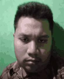 a close up of a man 's face against a green wall