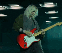 a blonde woman is playing a red electric guitar