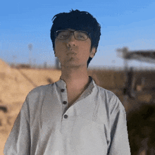 a man wearing glasses and a white shirt is standing in front of a blue sky