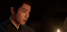 a man is sitting in a dark room with a candle in front of him .