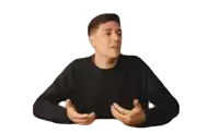 a man wearing a black sweater is sitting at a table with his hands outstretched .