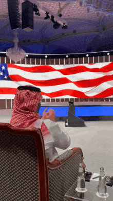 a man sits in front of an american flag