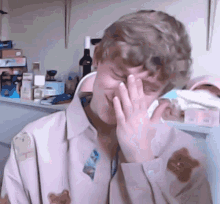 a young man is covering his face with his hand while wearing a pink shirt with bears on it .