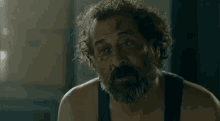 a man with a beard and curly hair is wearing a black tank top .