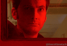 a close up of a man 's face with a red light behind him and the words @itsscottiesstark at the bottom