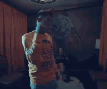 a man is dancing in a dark room with a table and chairs in the background .