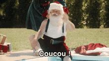 a man dressed as santa claus sits next to a pool with the words coucou written on the bottom
