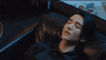 a man is laying on a black leather couch with his eyes closed