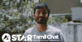 a blurred image of a man with a star tamil chat logo behind him