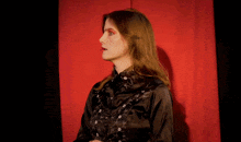 a woman in a black shirt is standing in front of a red background