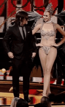 a man in a suit is standing next to a woman in a bikini