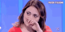 a woman is covering her nose with her hand while sitting on a blue table .