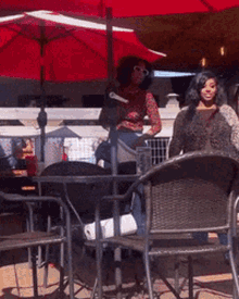 a woman is sitting at a table under an umbrella