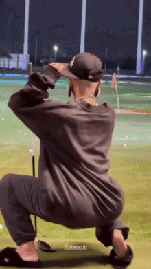 a man squatting on a golf course wearing a hat that says new york yankees