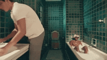 a woman is taking a bath in a bathtub while a man stands next to her .