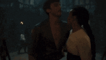 a man and a woman are standing in a dark room talking to each other