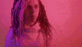 a woman with curly hair and glasses is standing in front of a red background .
