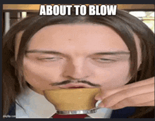 a man with long hair and a mustache is drinking from a cup with a caption that says about to blow .