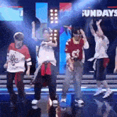 a group of young men are dancing on a stage with their hands in the air .