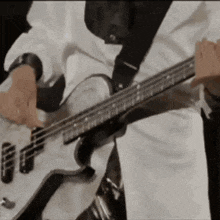 a man in a white shirt is playing a bass guitar