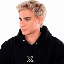a man wearing a black hoodie with the letter x on the front