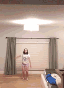 a young girl is jumping in the air in a bedroom