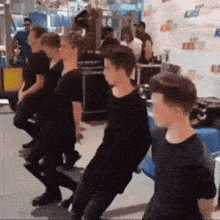a group of young men in black shirts are dancing in front of a wall that says kiss on it