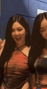 two women are standing next to each other and one of them is wearing a red top