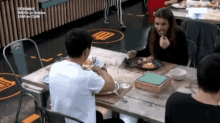 a group of people are sitting at a table in a restaurant eating