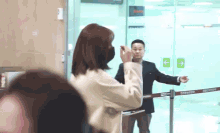 a woman wearing a mask stands next to a man in a suit behind a barrier that says exit