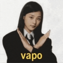 a woman in a suit and tie is making a no gesture with the word vapor behind her