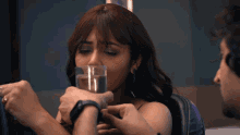 a woman drinking a glass of water while a man holds her hand