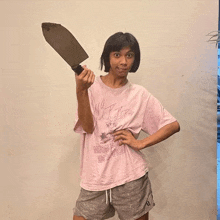a woman in a pink shirt holds a large knife