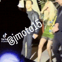 a woman in a green dress is standing next to a man in a suit and the number 15 is on the bottom of the image