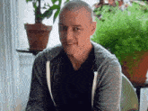 a man with a shaved head wearing a grey sweatshirt