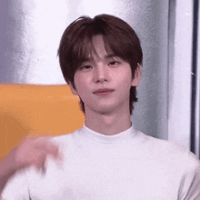 a young man with brown hair is wearing a white turtleneck sweater .