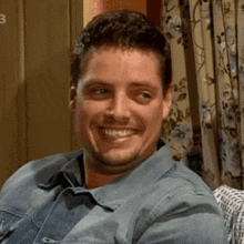 a man in a denim shirt is smiling in front of a door that says 3