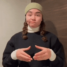 a woman wearing a beanie and a sweater is making a funny face