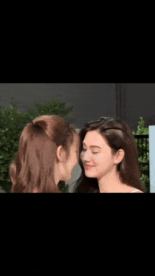 two young women are looking at each other and smiling