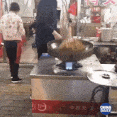 a person is cooking on a stove with a china daily logo on it
