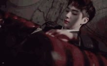 a young man in a suit is laying down on a red couch