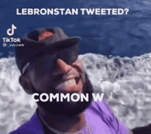 a man wearing sunglasses and a hat is standing in front of a body of water and says lebronstan tweeted ? common w