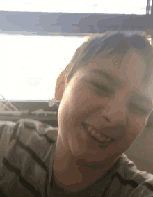 a close up of a young boy 's face with a window in the background