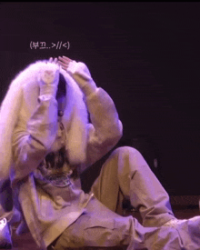a person covering their face with a fur coat with korean writing