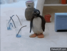 a penguin is standing next to a cup of water with a straw .
