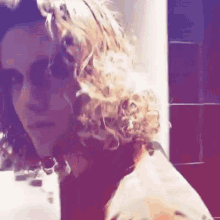 a woman with curly blonde hair looks at the camera